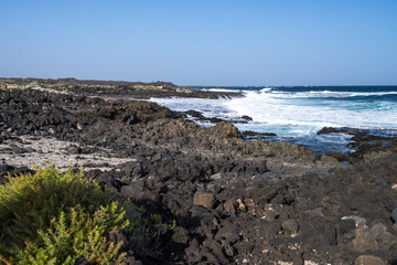 Black volcano stones and white sand on the coastline of  the Atlantic Ocean in Canarias
