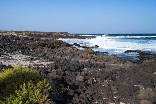 Fototapeta Black volcano stones and white sand on the coastline of  the Atlantic Ocean in Canarias  