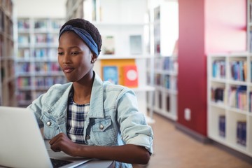 Schoolgirl using laptop in library