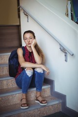 Portrait of sad schoolgirl sitting alone on staircase