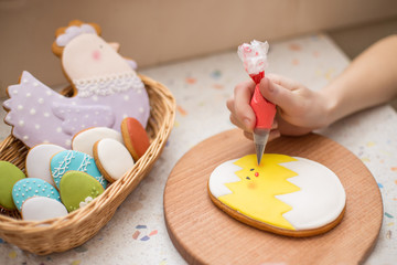 Cooking traditional Easter cookies. Woman hand decorate cookie at frosting. Easter food concept.