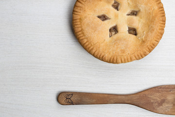 Apple pie cake lying on wooden white background with spoon