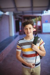 Happy schoolboy standing in school campus