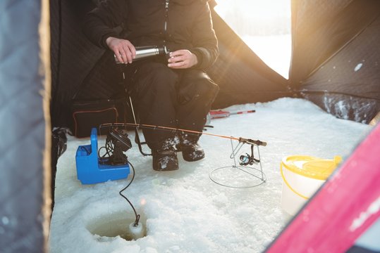 Ice fisherman drinking coffee in his tent