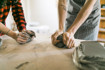 Two potters wedging clay in preperation for throwing