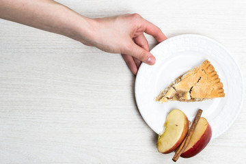 Fototapeta na wymiar Apple pie cake lying on wooden white background in hand