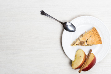 Apple pie cake lying on wooden white background with spoon