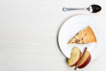 Apple pie cake lying on wooden white background with spoon