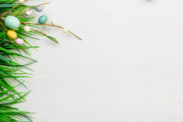 Easter spring colorful eggs and green grass lying on white wooden table background