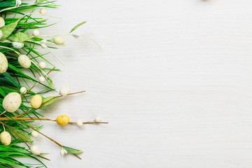 Easter spring colorful eggs and green grass lying on white wooden table background