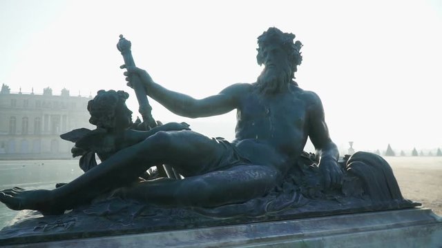 The statue of Neptune near the fountain on the background of the Versailles palace