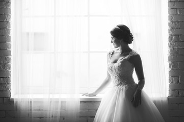Beautiful bride with bouquet before wedding ceremony near window