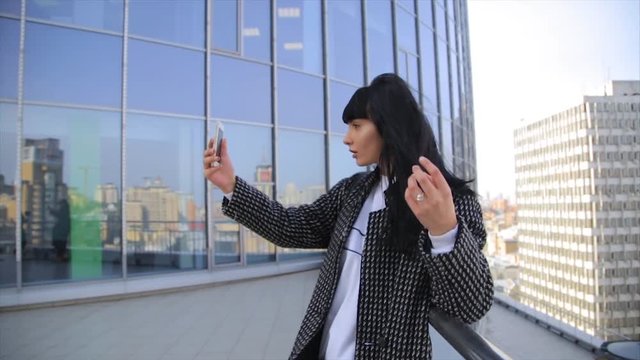 Fashion beautiful hispanic latina woman texting on smartphone in the city drinking latte coffee. Rooftop with cityview at background.