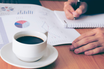 Image of coffee on desk of working businesspeople at meeting