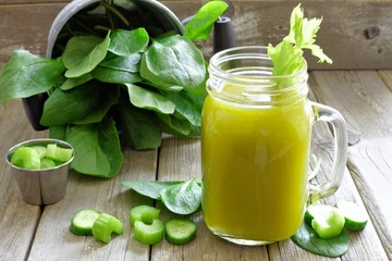 Healthy green vegetable juice in a mason jar glass, scene with rustic wooden background