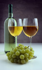 Bottle of white wine, grape on wooden table