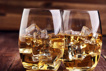 glass of whiskey with ice on a wooden