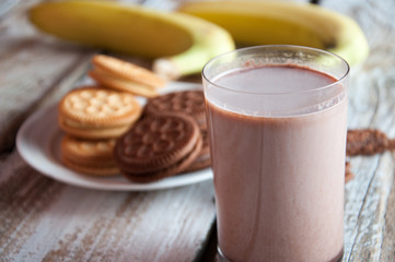 Photo of fresh Made Chocolate Banana Smoothie on a wooden table with cookies.