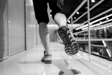 Fototapeta na wymiar Running sport. Man runner legs and shoes in action at sport shop. Shoot in black and white shot.