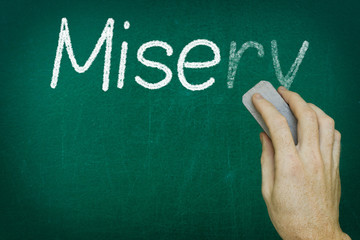 Hand erasing the word MISERY written on blackboard