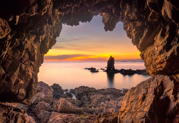 fisherman standing in front of a cave entrance at sunset