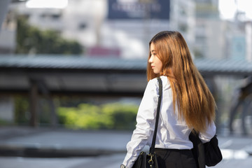 Back view of standing beautiful blonde business woman, backside view of person in modern city