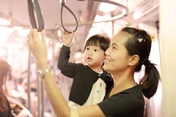 Mother carrying daughter in sky train.