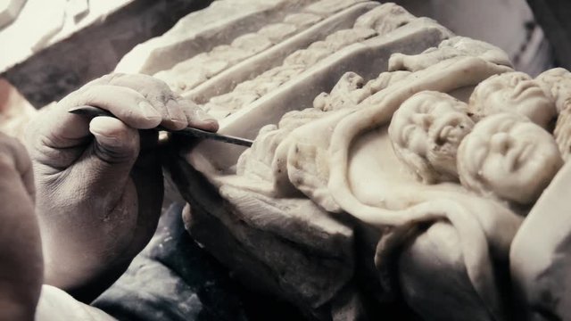 Hands of an latin expert craftsman, stone sculpting with chisel and hammer. Slow motion