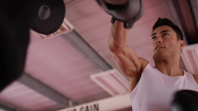 4K Low angle of asian male doing boxing pad work with trainer