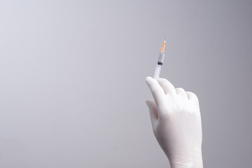 Hand wearing latex glove holding syringe with a medicine