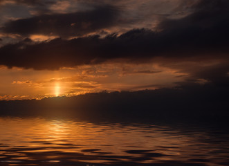 Dramatic sunset with clouds reflected in water.