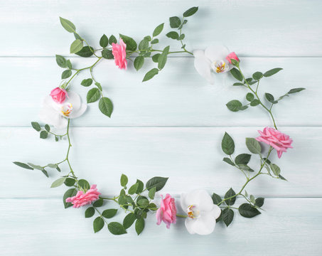 Wooden background with floral frame consists of roses and orchid flowers