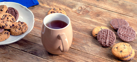 Cup of tea and cookies on a wooden table.