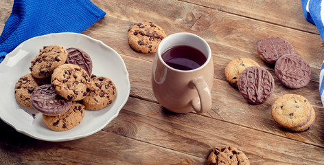 Cup of tea and cookies on wooden table.
