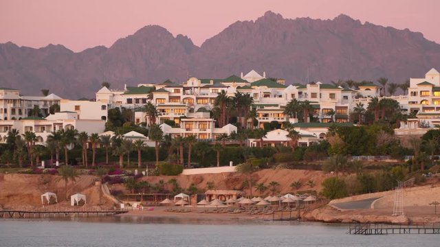 Beach and houses in the background of the mountains at dawn.