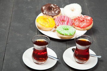 Cups of tea and donuts on a black wooden background