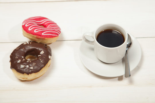 Cup with coffee and donuts on a white wooden table