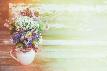 spring background with wild flowers in a white jug in soft sunlight