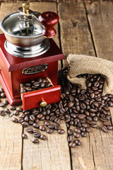 coffee beans in jute bag with coffee grinder on wood.