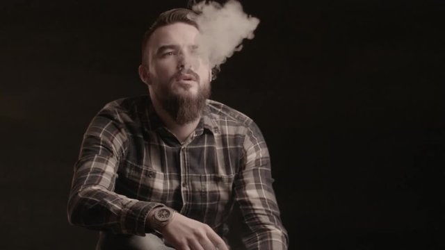 Handsome man with a beard smoking cigar in studio. Video,shot