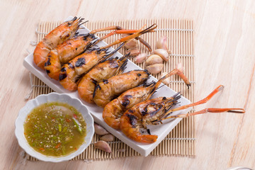 Burn shrim and Seafood sauce on wooden table.