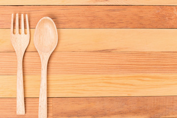 Top view of wooden fork and spoon on light wooden background.