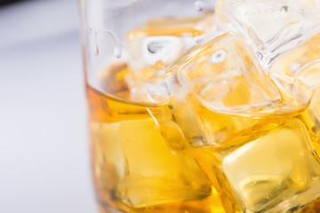 Glass of scotch whiskey and ice on a white background.