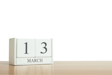 Closeup surface white wooden calendar with black 13 march word on blurred brown wood desk isolated on white background with copy space , selective focus at the calendar