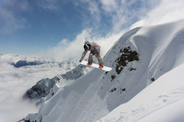Naklejka na ściany i meble Extreme winter sport. Snowboarder jumping in snowy mountains.
