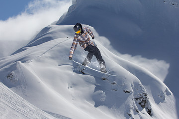 Extreme winter sport. Snowboarder jumping in snowy mountains.