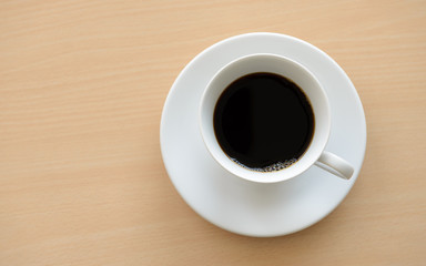 Top view of a cup of hot coffee on wooden table