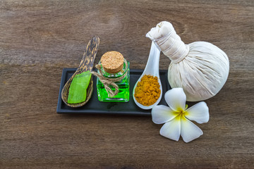 Spa herbal (white frangipani flowers, pill,Aloe vera essential oil and gel,compressing ball turmeric powder) on wooden background