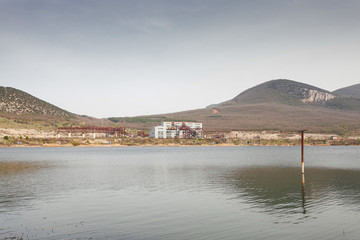 A lake in the foothills of the mountain of the city. The abandoned factory of the times of the Cold War of the USSR