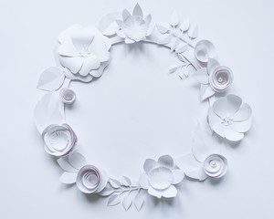 Round frame with white paper flowers on white background. Cut from paper.